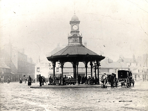 Black and white view of the Bridgeton Cross Shelter, an octagonal shelter supported on slim columns with a short clock tower above.