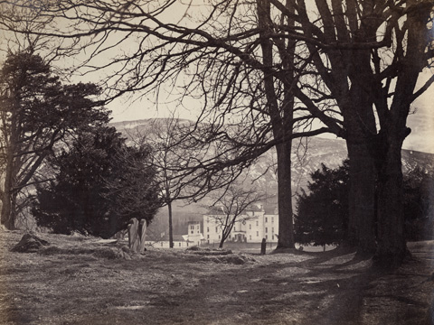 Black and white view of Blair Castle seen through trees from the graveyard of St Bride's Church