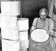 A photograph showing a Victorian woman working on making hat boxes