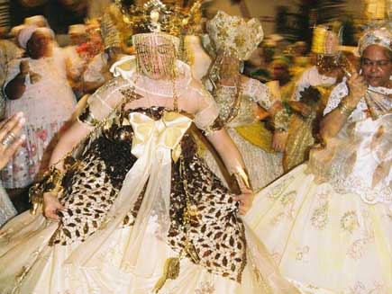 Woman in an elaborate dress wearing a gold plated crown, dancing.