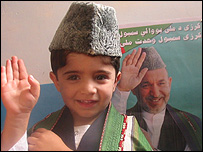 کودک افغان در کنار پوستر حامد کرزی