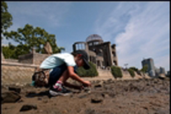 Child catches crabs in a drybed of the Motoyasu river next to the Hiroshima Dome.