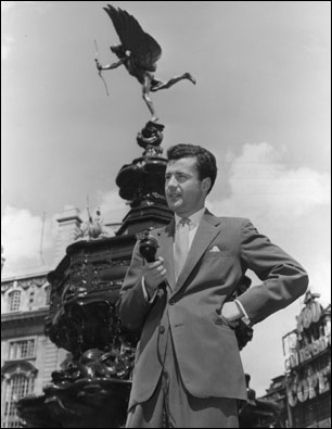 Londra'daki Piccadilly meydanında Eros heykelinin önünden meydanı dinleyicilere tarif eden BBC Türkçe yapımcısı Özcan Ergüder. İki Şehir programının o ayki bölümü Londra'nın Batısı ve İstanbul'un Avrupa yakasını buluşturuyordu. 14/06/1956 © BBC