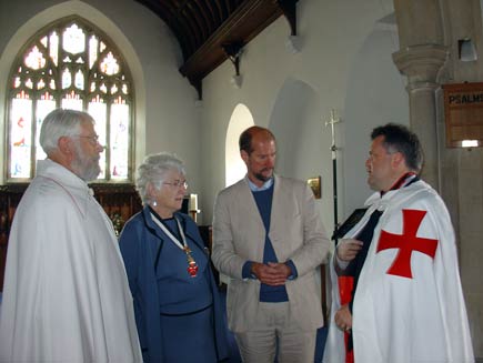 Martin Palmer, third from left, talking to three people. The two other men wear traditional Templar mantles, white with a red splayed cross visible on one side, and the woman is wearing the same red cross symbol around her neck