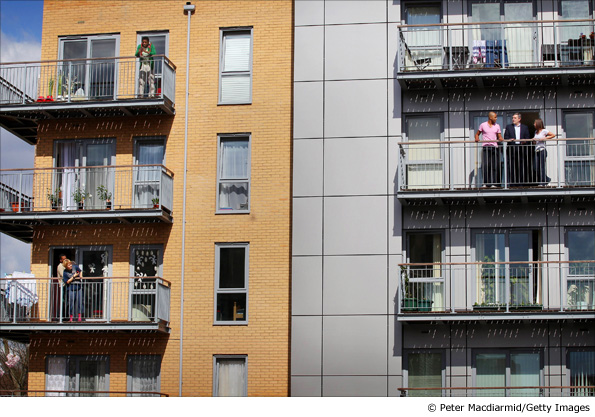 People look across as Gordon Brown as he talks to residents on the balcony of their newly built flat in London