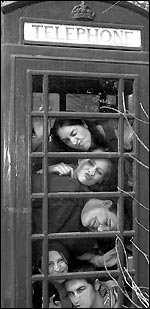 The members of Pineapples Don't Grow on Trees! squashed into a phone box