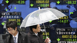 Men walking past share price board