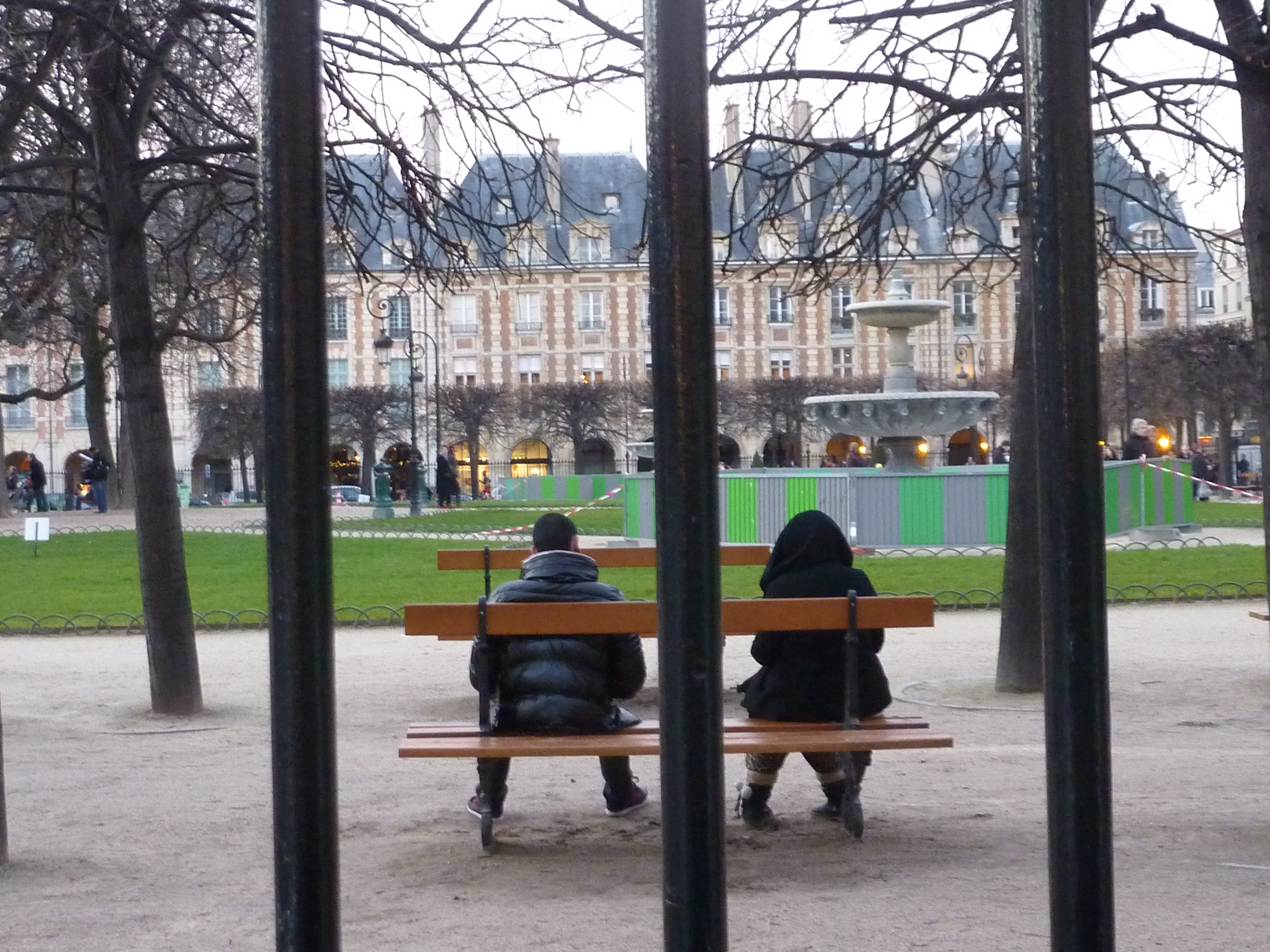A young couple on a park bench sitting apart.