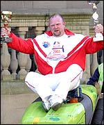 Mark sat on a dust cart holding his trophies