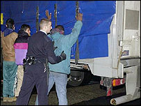 ایک تارک وطن کی تلاشی لیتا ہوا پولیس والا