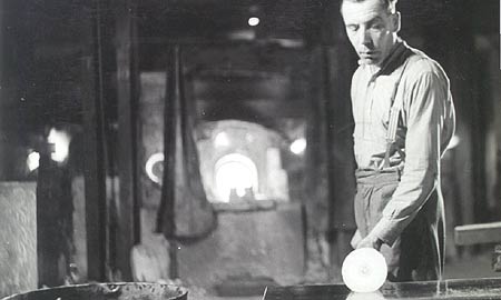 Worker rolling and shaping glass