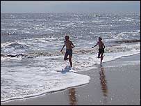 Two boys run along the sun-drenched beach
