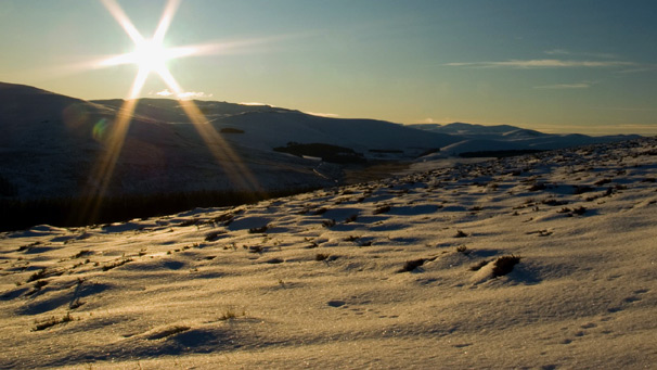 A low sun over a mountain snowscape
