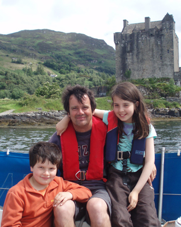 Father, son and daughter in yacht moored in front of a castle in Scotland