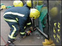 Fire fighters cut into the wreckage of a car