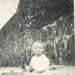 One year old Neil Pedlar in 1941 on the sand at Porth Beach, Newquay, Cornwall, defended from the Nazi forces by barbed wire seen on top of wall.
