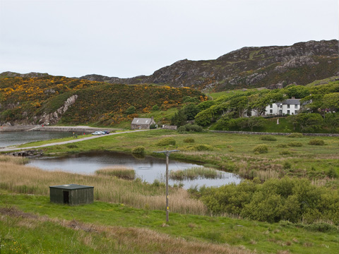 Colour view of the back of a row of modern retail outlets with the skyline of Coatbridge behind.