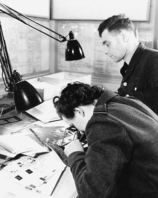 A WAAF section officer examines reconaissance photos