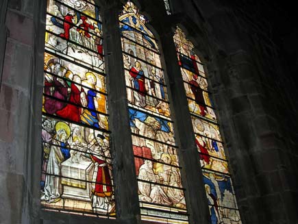 Full view of the three arched windows holding the stained glass panels of St Bernard