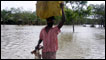 Man carrying belongings on his head in flood water in Bangladesh