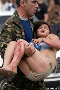 Rus asker, Beslan'da okul baskınından kurtarılan yaralı çocuğu olay yerinden uzaklaştırıyor