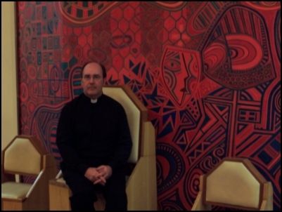 Father Gerard Robinson in front of the Reredos