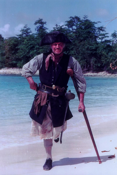 Long John Silver standing on a beach.