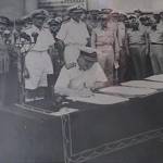 Admiral Sir Bruce Fraser signing the surrender terms on behalf of the British Government and the Crown.General McArthur is to the left of the picture
