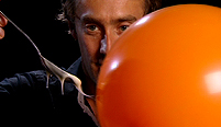 Dallas Campbell holds the cornflour slime up to a static balloon.