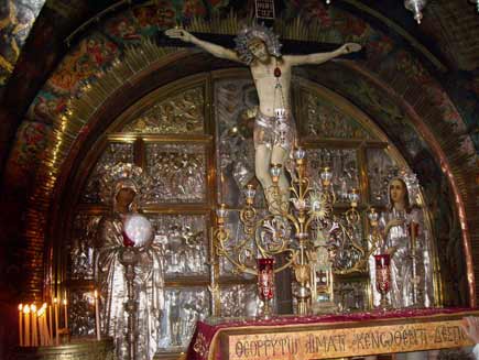 Icon of Jesus on the cross, carvings, candles and an eclectic selection of shiny ornaments are set up in the church