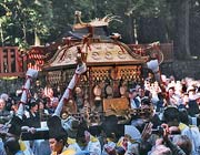A gold-coloured mikoshi being carried by believers at a shrine