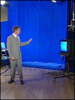 Richard in the studio. The computer to the left of Richard generates the charts, and he can see the composite on the monitor to the right of the picture