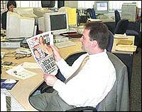 Dominic reading a paper in the newsroom
