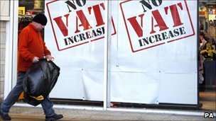 Man walking infront of a Sports Direct store in Liverpool advertising no VAT increase in their store