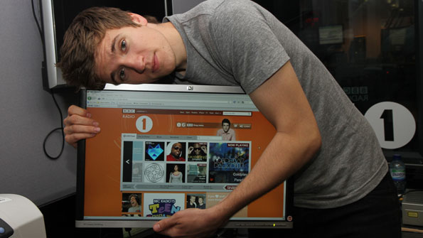 Young man in Radio 1 studio hugs a monitor showing the new home page