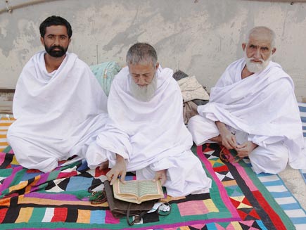 Three men sitting down dressed in Ihram
