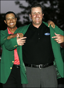 Phil Mickelson receives the famous Green Jacket from Tiger Woods after winning last year’s Masters