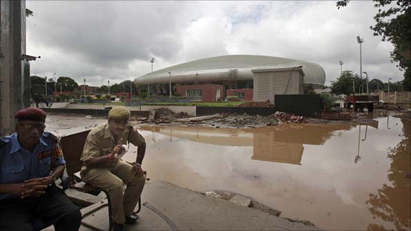 Security personnel try to stop photographs near the waterlogged weightlifting stadium in Delhi
