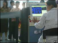 Funcionária da área de saúde monitora a temperatura de passageiros no aeroporto de Pequim com uma máquina