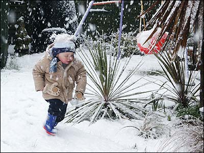 Young boy enjoying the snow in the garden