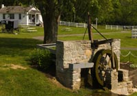Stone waterwheel in an Amish village. A horse buggy is visible in the distance