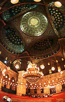 High domed roof and brightly-lit interior of a mosque