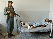 سرباز افغان در حال نگهبانی از زندانی زخمی طالبان