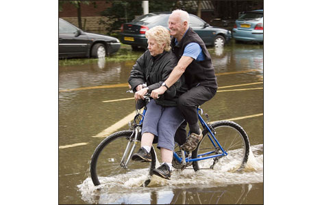 Couple ride through floods on a bike