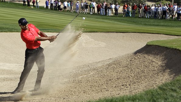 Tiger Woods plays a shot from a bunker