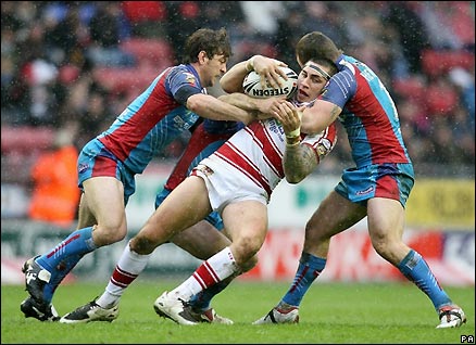 Wigan's Harrison Hansen is tackled by three Wakefield players during their opening fixture of Super League XIV