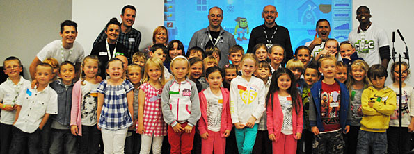 Dozens of children standing in front of some adults wearing BBC badges.