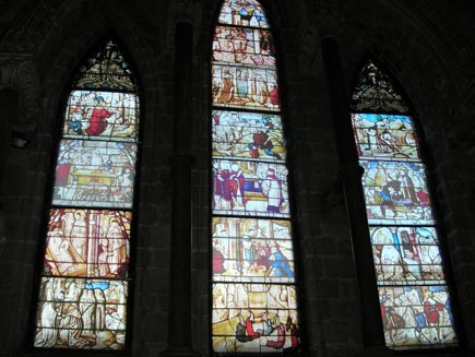 Three arched windows in the church wall, showing the temporary replacement windows.