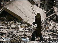 Mulher olha prédio destruído