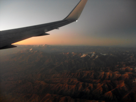 Photo of the sun in the sky taken through the window of a plane